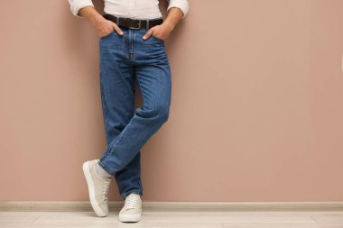 Bej duvarın yanında şık kotlu bir adam, yakın plan. Metin için boşluk