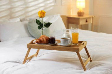 Otel odasında yatakta nefis bir kahvaltı tepsisi.