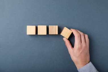 Gri arka planda tahta küpleri olan adam, üst manzara.