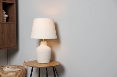Evdeki beyaz duvarın yanındaki ahşap masada şık lamba, metin için yer