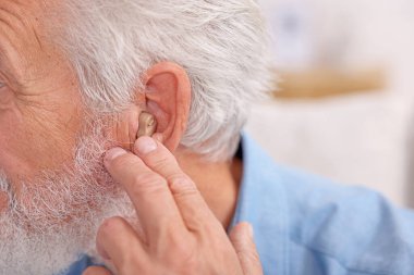 İçeride işitme cihazlı kıdemli adam, yakın plan.