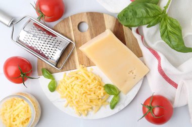 Öğütücü, domates, fesleğen, rendelenmiş peynir ve beyaz masa, düz uzanmış