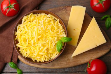 Tahta masanın üzerinde domatesli rendelenmiş peynir parçaları, düz uzanmış.