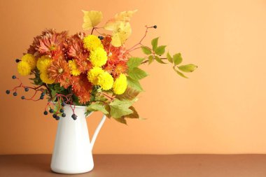 Sonbahar atmosferi. Üzerinde güzel çiçekler ve böğürtlenler olan vazo turuncu arka planda, metin için boşluk