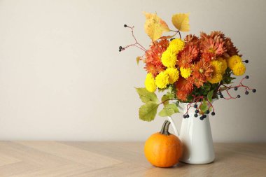 Sonbahar atmosferi. Güzel çiçekli vazo, böğürtlen ve balkabağı ahşap masada, yazı için yer