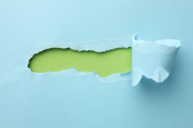 Yeşil arka planda yırtık deliği olan açık mavi kağıt, üst manzara. Metin için boşluk