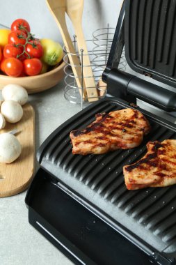 Mutfaktaki ışık masasında nefis biftek ve sebzelerle elektrikli ızgara.