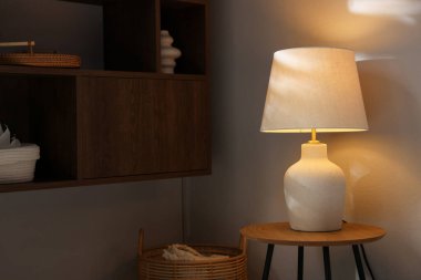 Evdeki ışık duvarının yanındaki ahşap masada şık bir lamba.