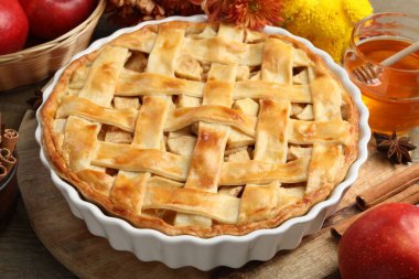 Lezzetli ev yapımı turta, taze elmalar, bal ve çiçekler ahşap masada, yakın plan.