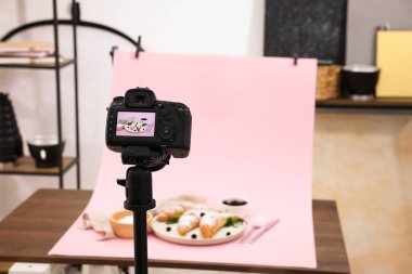 Stüdyoda kamera ile lezzetli kruvasanlar ve malzemeler çekmek, seçici odaklanma. Profesyonel yemek fotoğrafçılığı.