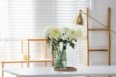 Beyaz masadaki vazoda duran güzel kasımpatı çiçekleri.