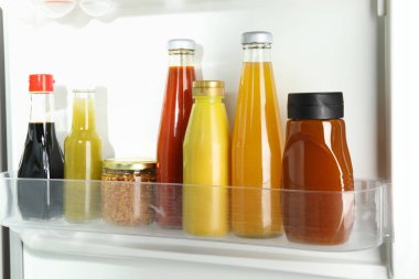 Dolapta farklı lezzetli soslar olan şişeler, yakın plan.