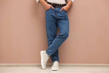 Bej duvarın yanında şık kotlu bir adam, yakın plan.