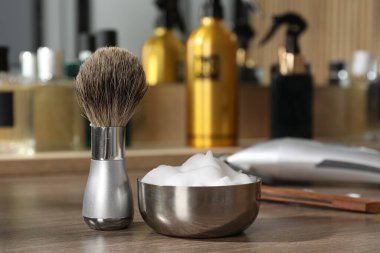 Berber dükkanındaki ahşap masada tıraş fırçası ve köpük, yakın plan.