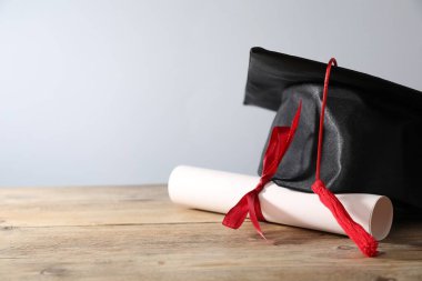 Mezuniyet şapkası ve diploması ahşap masada, yakın plan. Metin için boşluk