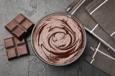 Erimiş çikolata ve parçalarla dolu bir kase siyah masanın üzerinde, düz bir şekilde.