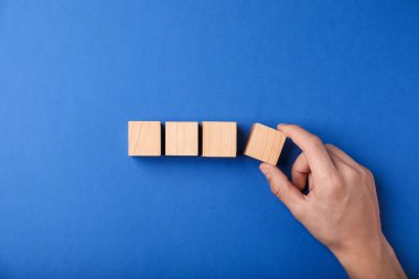 Mavi arka planda tahta küpleri olan adam, üst manzara.