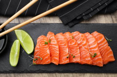 Tahta masada servis edilen yeşil limon ve soya soslu taze somon balığı.