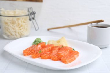 Mikro yeşillikli taze somon balığı, wasabi, zencefil ve soya sosu açık fayanslı masada, yakın plan.