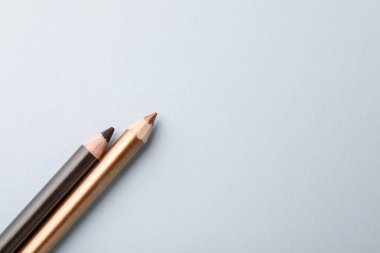 Hafif arka planda renkli göz kalemleri, düz yatış. Metin için boşluk