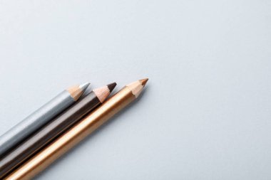 Hafif arka planda renkli göz kalemleri, düz yatış. Metin için boşluk