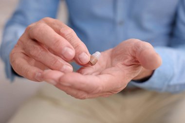 İçeride işitme cihazlı kıdemli adam, yakın plan.