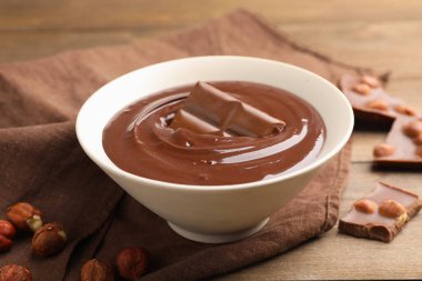 Erimiş çikolata ve fındıklı ahşap masa, yakın plan.