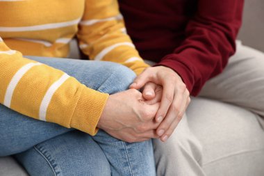 Anne ve oğul evdeki kanepede el ele tutuşuyorlar, yakın çekim.