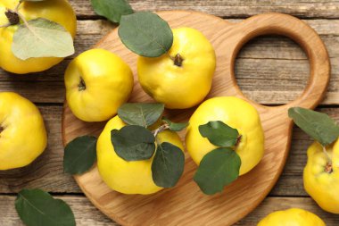 Tahta masadaki yapraklarla taze, olgun ayvalar.