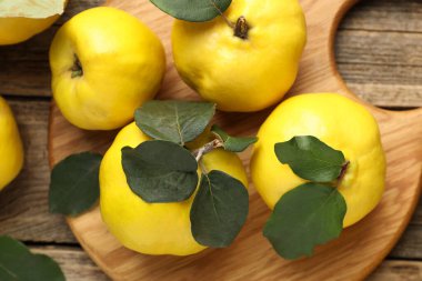 Tahta masadaki yapraklarla taze, olgun ayvalar.