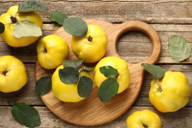 Tahta masadaki yapraklarla taze, olgun ayvalar.