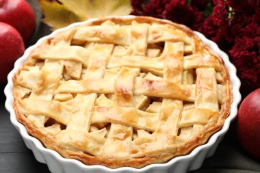 Lezzetli ev yapımı turta, taze elma ve çiçekler siyah ahşap masada, yakın plan.