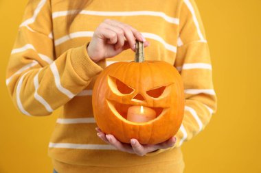 Mutlu Cadılar Bayramı. Sarı arka planda balkabağı kabağı oyulmuş kadın, yakın plan.