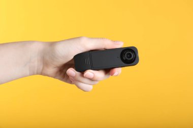 Sarı arka planda gizli casus kamerası olan kadın, yakın plan.