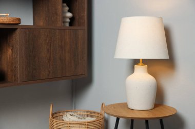 Evdeki beyaz duvarın yanındaki ahşap masada şık bir lamba.