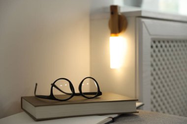 Puf gözlüklü kitaplar ve evdeki portatif LED lamba. Metin için boşluk
