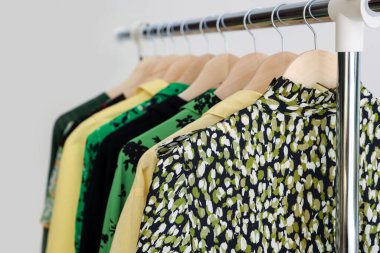 Arka planda askıda asılı farklı kıyafetler, yakın plan