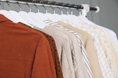 Gri arka planda askıda asılı farklı kıyafetler, yakın plan