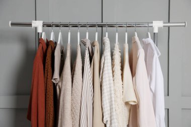 Gri duvarın yanında asılı farklı elbiseler.