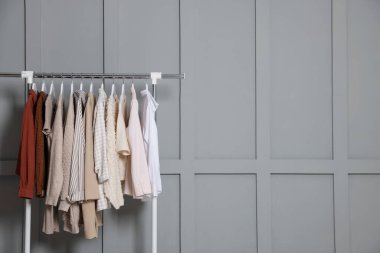 İçerideki gri duvarın yanında farklı kıyafetler asılı. Metin için boşluk