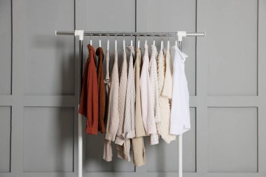 Gri duvarın yanında asılı farklı elbiseler.