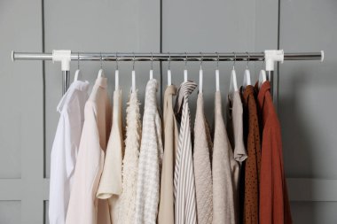 Gri duvarın yanında asılı farklı elbiseler.