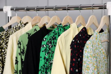 Gri duvarın yanında asılı farklı giysiler, yakın plan.