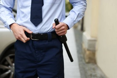 Şehir sokağında coplu bir polis memuru, yakın plan.