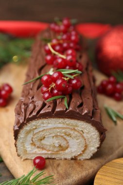 Lezzetli Noel kütüğü (geleneksel Noel pastası) ahşap masa üzerinde kırmızı frenk üzümü, yakın plan