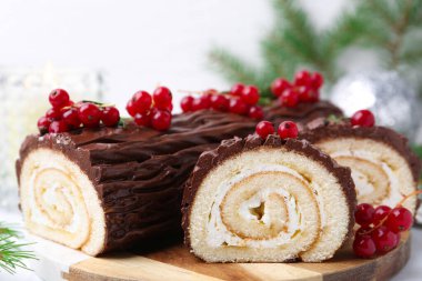 Lezzetli Noel kütüğü (geleneksel Noel pastası) masada kırmızı frenk üzümü, yakın plan