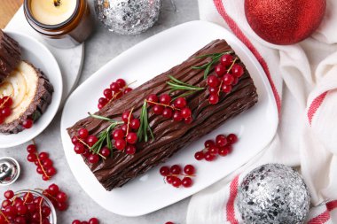 Lezzetli Noel kütüğü (geleneksel Noel pastası) kırmızı frenk üzümü ve gri desenli masa, düz uzanma