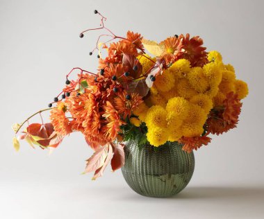 Sonbahar atmosferi. Güzel çiçekli vazo ve açık gri arka planda böğürtlen