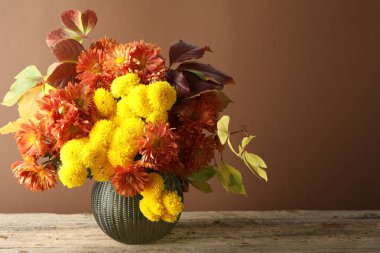 Sonbahar atmosferi. Güzel çiçekli vazo ve ahşap masa üzerinde kahverengi arkaplan, metin için boşluk