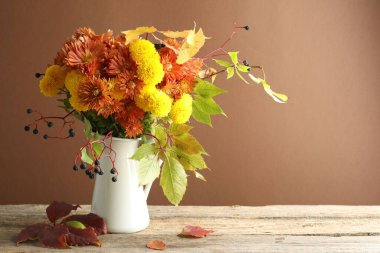 Sonbahar atmosferi. Güzel çiçekli vazo, böğürtlen ve yapraklar ahşap masa üzerinde kahverengi arkaplan, metin için alan